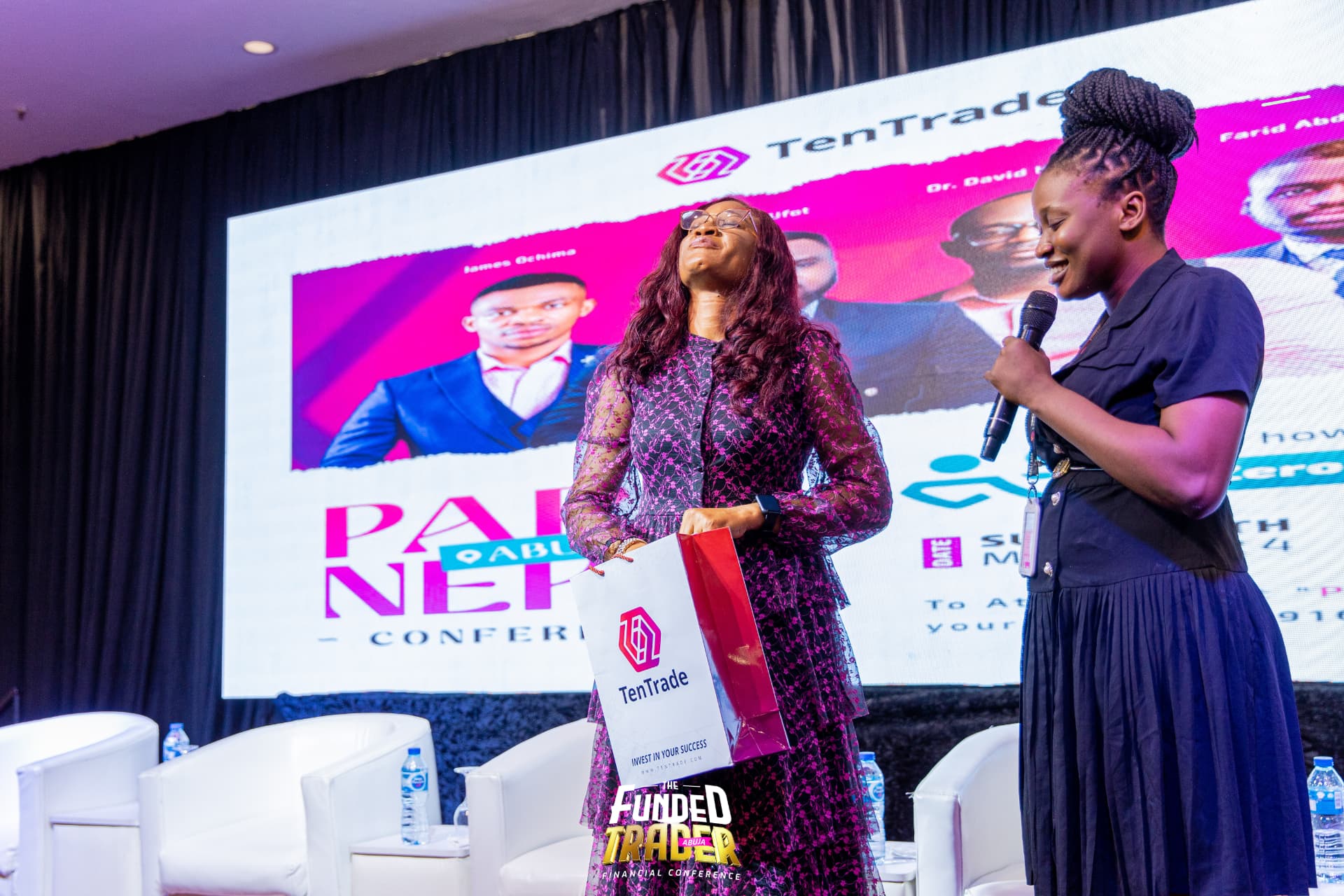 Handing a TenTrade gift bag to an attendee on stage in Abuja